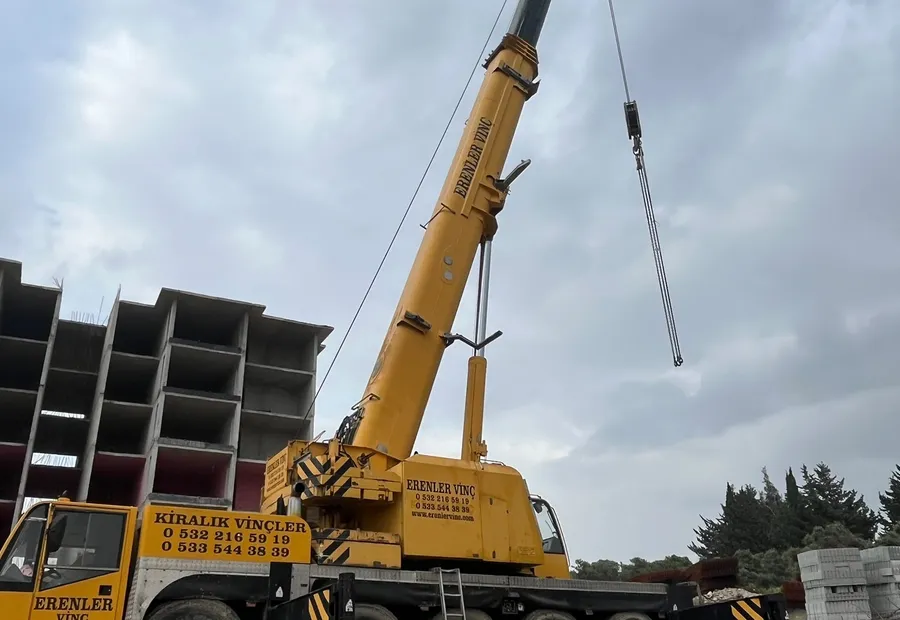 İnşaat şantiyesinde ağır kaldırma yapan sarı mobil vinç